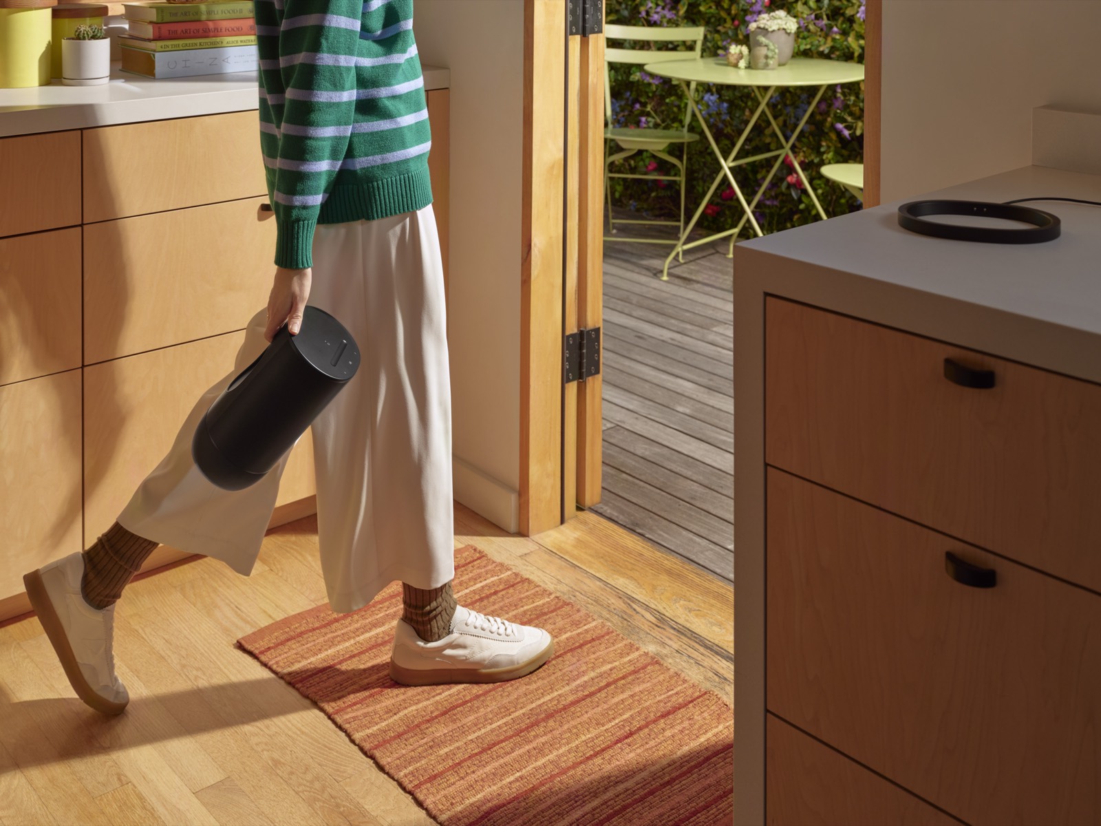 A portable speaker being carried from the kitchen out to the patio