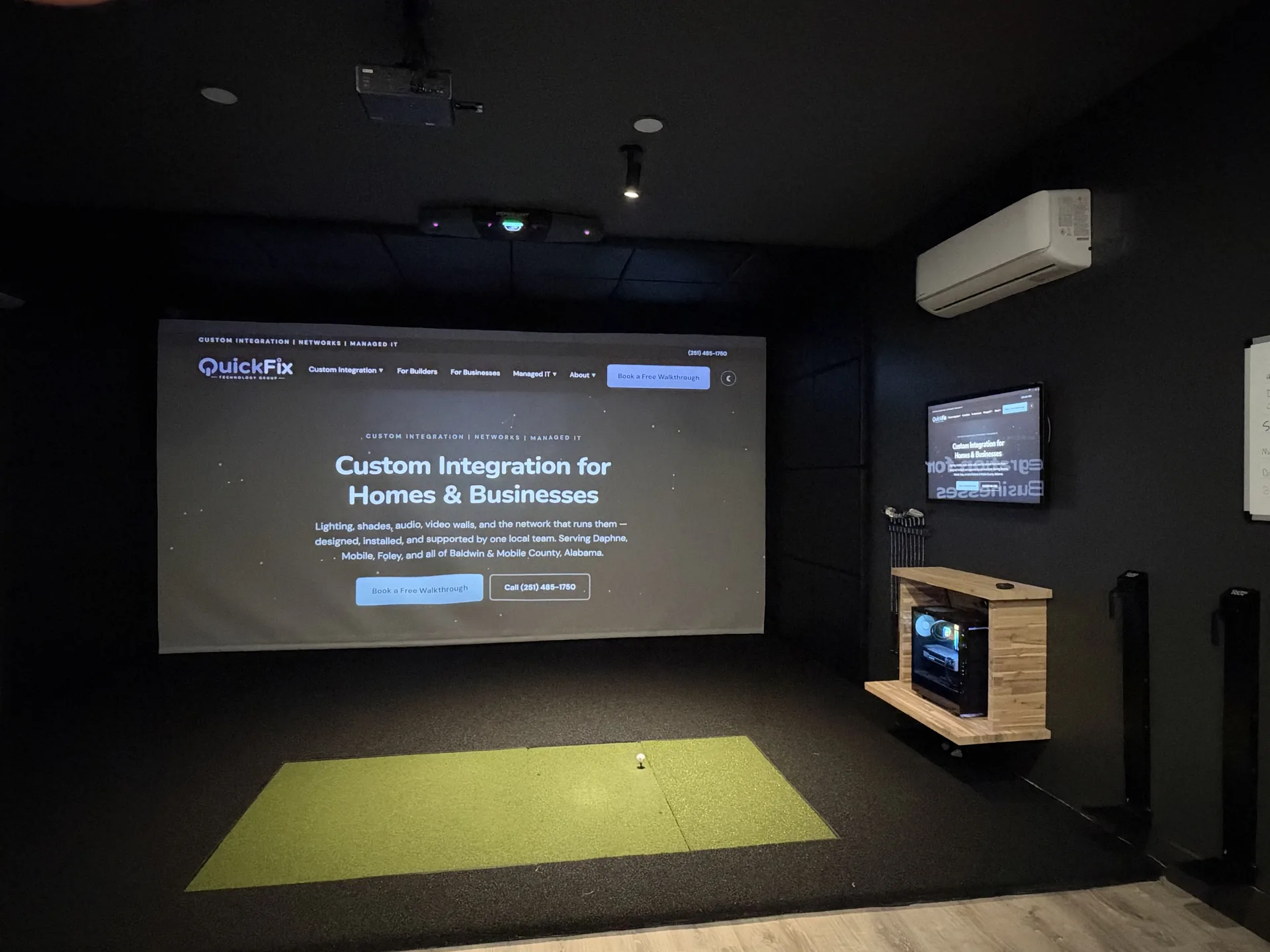 Finished private golf simulator room with projection screen, putting turf, and lounge seating